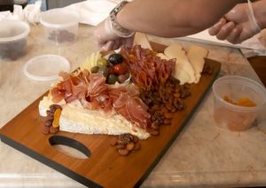 The chef placing cheese and charcuterie on a board for serving