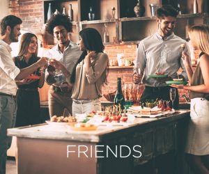 Mobile version of a gathering of friends in the kitchen of a home toasting with wine with the words FRIENDS across the image